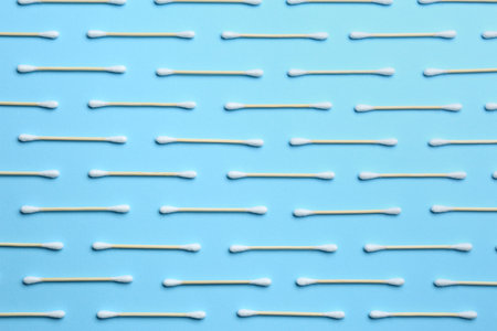 Many cotton buds on light blue background, flat lay