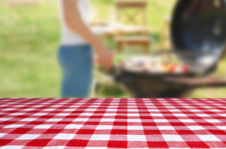Table with checkered picnic cloth outdoors on sunny day. space for designの写真素材