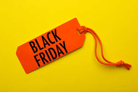 Orange tag with phrase BLACK FRIDAY on yellow background, top viewの写真素材