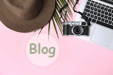Blogger's workplace with laptop and camera on pink background, flat lay