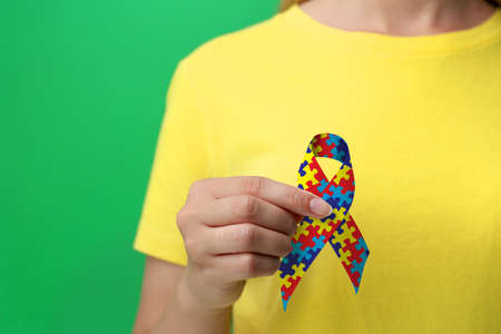 World Autism Awareness Day. Woman with colorful puzzle ribbon on green background, closeupの写真素材