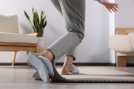 Woman tripping over carpet at home, closeup