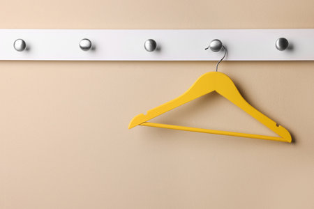 Rack with empty yellow clothes hanger on beige wallの写真素材