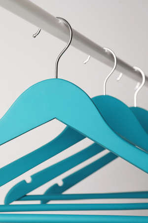 Empty turquoise clothes hangers on metal rail against light gray background, closeupの写真素材