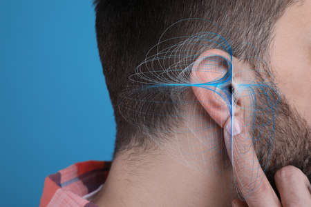 Hearing loss concept. Man and sound waves illustration on light blue background, closeupの写真素材