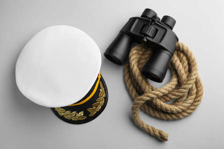 Peaked cap, rope and binoculars on light gray background, flat layの写真素材