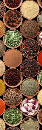 Collection of different aromatic spices and herbs on black background, flat lay. vertical banner...