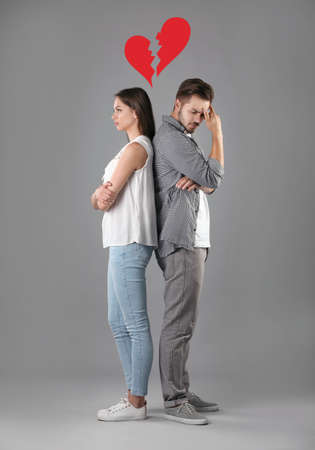 Upset young couple and illustration of broken heart on gray background. relationship problemsの写真素材