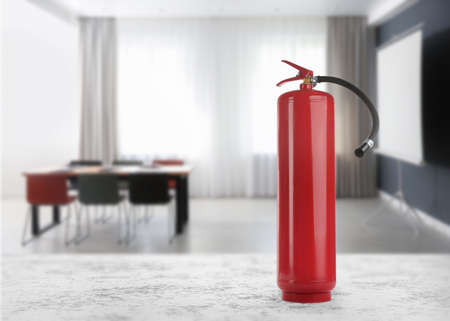 Fire extinguisher on stone table in meeting room. Space for textの写真素材
