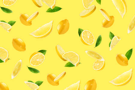 Fresh ripe lemons and green leaves flying on yellow background