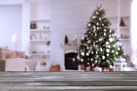 Empty wooden table in festively decorated room with Christmas tree near fireplace. space for designの写真素材