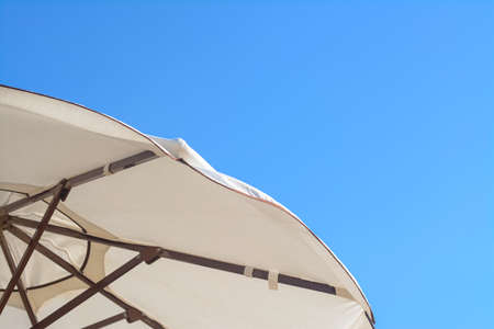 Beautiful white beach umbrella against blue sky, closeup. Space for textの写真素材