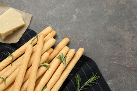 Delicious grissini with rosemary and cheese on gray table, flat lay. Space for textの写真素材