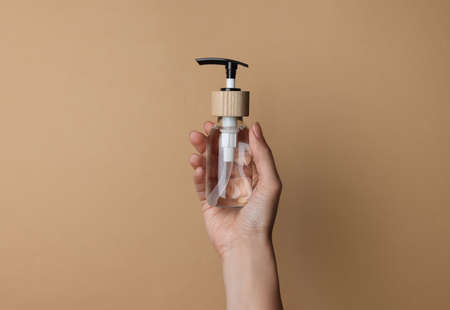 Woman holding bottle of cosmetic product on beige background, closeupの写真素材