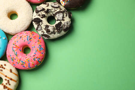 Sweet tasty glazed donuts on green background, flat lay. Space for textの写真素材