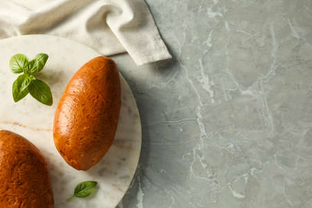 Tasty freshly baked pirozhki and basil on light gray marble table, top view. Space for text