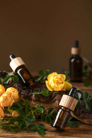 Bottles of rose essential oil and flowers on wooden tableの写真素材