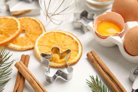 Cookie cutters, dried orange slices, cinnamon sticks and eggs on white table. christmas biscuitsの写真素材