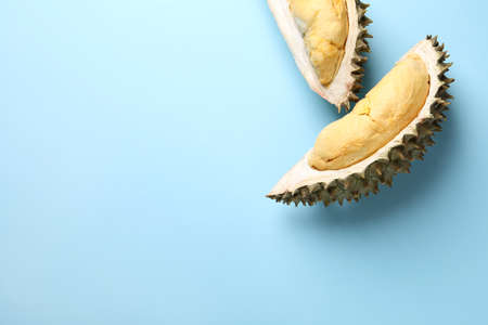 Pieces of fresh ripe durian on light blue background, flat lay. Space for textの写真素材