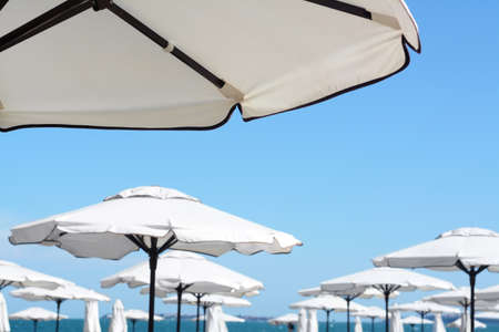 Beautiful white beach umbrellas against blue skyの写真素材