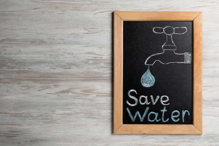 Blackboard with words Save Water and drawn tap on wooden table, top view. Space for textの写真素材