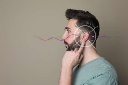 Hearing loss concept. Handsome man and sound waves illustration on beige background, closeupの写真素材
