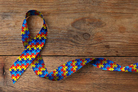 World Autism Awareness Day. Colorful puzzle ribbon on wooden background, top viewの写真素材
