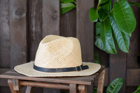 Stylish hat on wooden stool near fence. Beach accessories