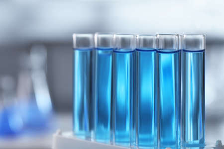 Test tubes with light blue liquid on blurred background, closeupの写真素材
