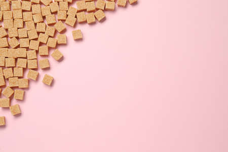 Brown sugar cubes on pink background, flat lay. Space for textの写真素材