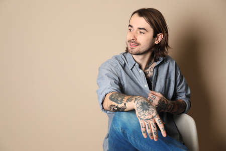 Young man with tattoos on body against beige background. Space for textの写真素材