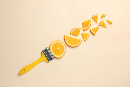 Creative flat lay composition with paint brush and slices of orange on beige backgroundの写真素材
