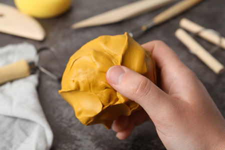 Woman holding clay over gray stone table with modeling tools, closeupの写真素材