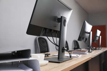 open office interior. Modern workplaces with computers near light gray wall