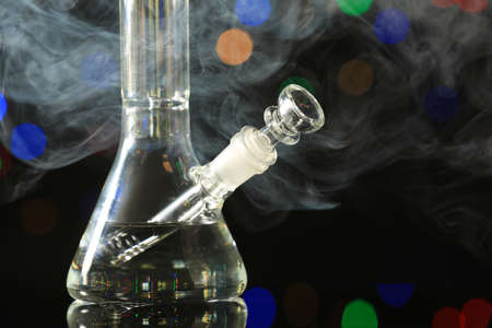 Closeup view of glass bong with smoke against blurred lights. smoking deviceの写真素材