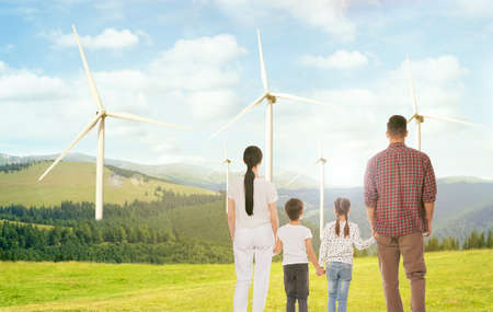 Family with children looking at wind energy turbines on sunny dayの写真素材
