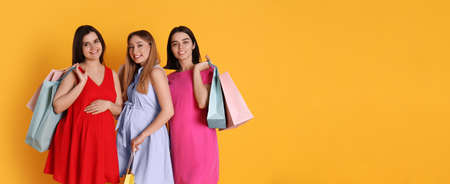 Happy pregnant women with shopping bags on orange background, space for text. banner design
