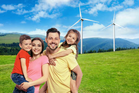 Happy family with children and view of wind energy turbines on sunny dayの写真素材