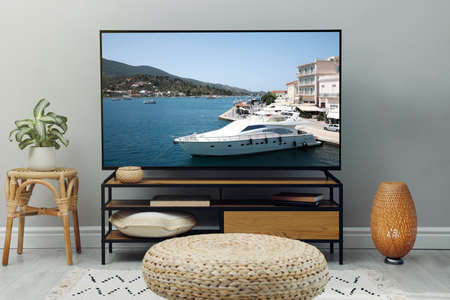 Modern TV set on wooden stand in room