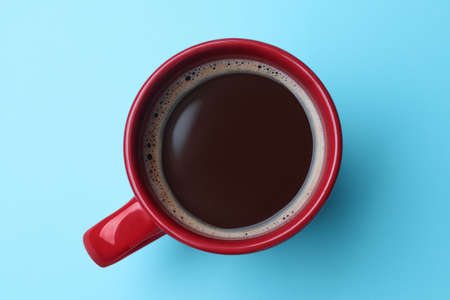 Red mug of freshly brewed hot coffee on light blue background, top viewの写真素材