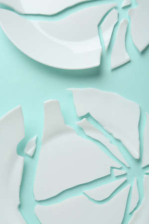 Two broken ceramic plates on light blue background, flat layの写真素材