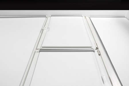 Window with closed white roller blinds indoors, low angle view