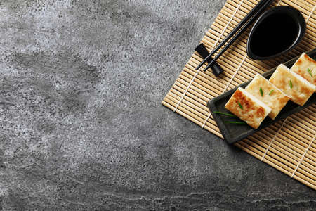 Delicious turnip cake with green onion, soy sauce and chopsticks on gray table, top view. Space for textの写真素材