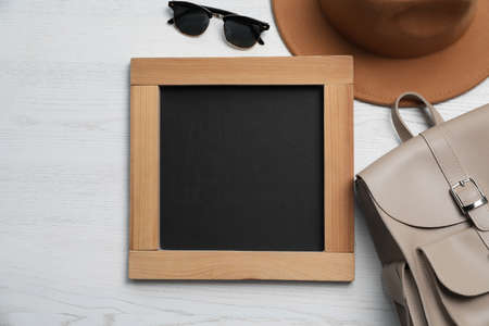 Blank chalkboard with stylish accessories on white wooden table, flat lay. Space for textの写真素材