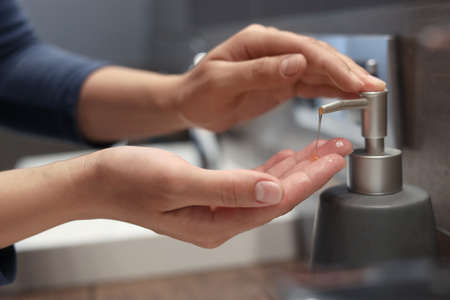 Woman using liquid soap dispenser in bathroom, closeupの写真素材
