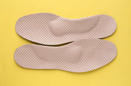Beige orthopedic insoles on yellow background, flat layの写真素材