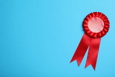 Red award ribbon on turquoise background, top view. Space for textの写真素材
