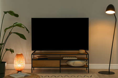Stylish wide TV set on stand in room