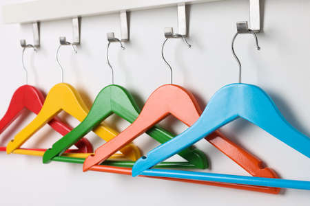 Rack with empty clothes bright hangers on white wallの写真素材