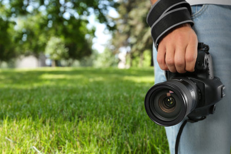 Professional photographer with modern camera and blurred view of park, space for textの写真素材